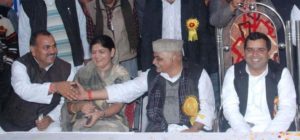 मंच पर हाथ मिलाते नरेश प्रताप सिंह और भारत सिंह यादव एवं ठहाके लगाते सांसद धर्मेन्द्र यादव व पूनम यादव 