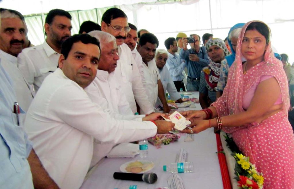 महिला लाभार्थी को परिचय पत्र देते सांसद धर्मेन्द्र यादव व मंत्री अवधेश प्रसाद। 