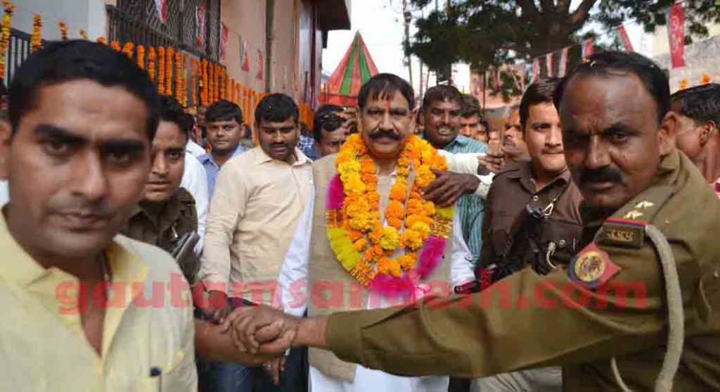 पुलिस के घेरे के बीच आगे बढ़ते ग्राम्य विकास राज्यमंत्री ओमकार सिंह यादव।