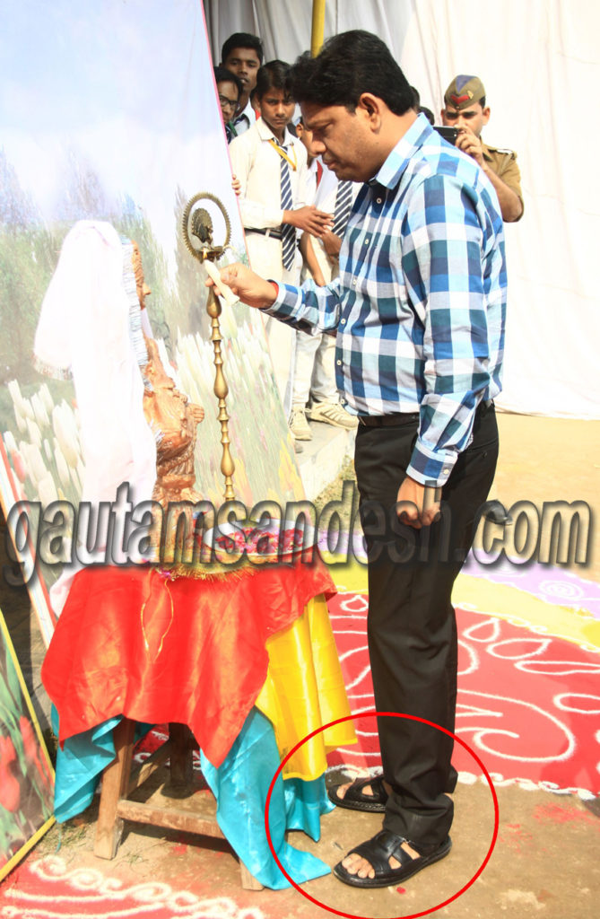 चप्पलें पहन कर माँ सरस्वती की प्रतिमा के समक्ष दीप प्रज्ज्वलित करते जिलाधिकारी पवन कुमार।